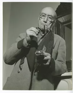 portrait photographique d’André Gide, avec lunettes, près d'un miroir, s'allumant une cigarette, chez Richard Heyd, hiver 1947